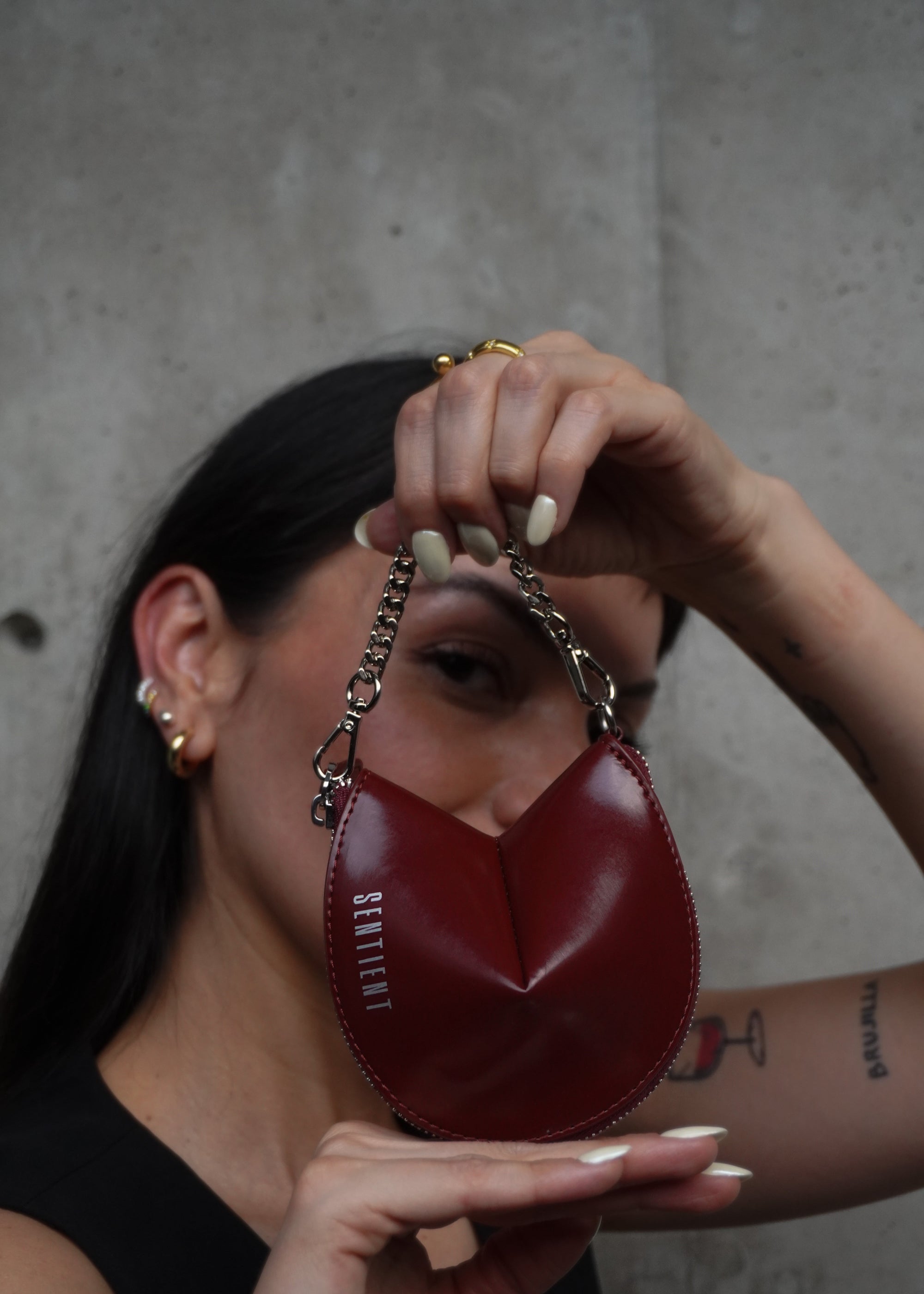 A person holding up a red sentient fortune cookie-shaped charm with a silver chain and detailing.